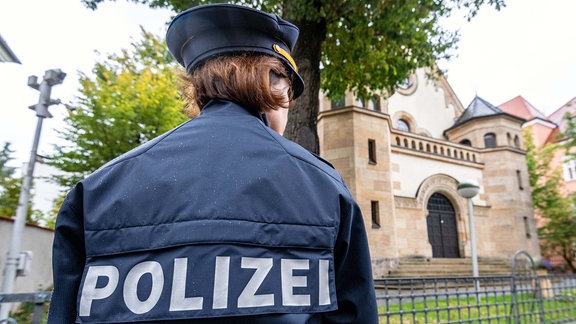 Eine Polizistin steht vor der Synagoge. Nach dem Anschlag auf eine Synagoge in Halle/Saale hat die Polizei ihre Präsenz vor jüdischen Einrichtungen im Freistaat erhöht.