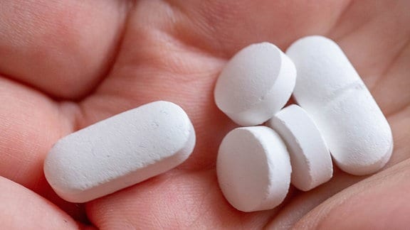 Tabletten und Vitaminpräparate in einer Hand