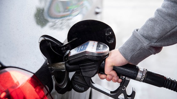 Ein Autofahrer steckt an einer Tankstelle einen Diesel-Zapfhahn in die Tanköffnung seines Fahrzeugs.