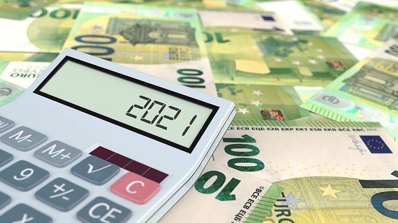 Ein Taschenrechner auf 100-Euro-Scheinen zeigt die Zahl 2021