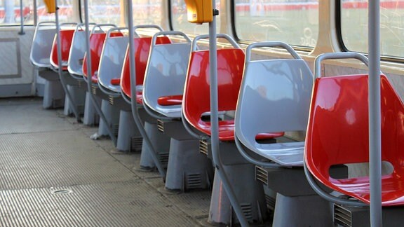 Im Innenraum einer Tatra-Straßenbahn sind leere Sitzschalen hintereinander aufgereiht in den Farben rot und grau
