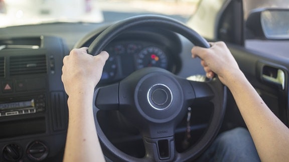 Männerhände halten Lenkrad in einem Auto