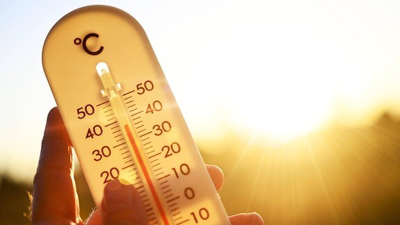 Hand hält Thermometer bei über 30 Grad Celsius