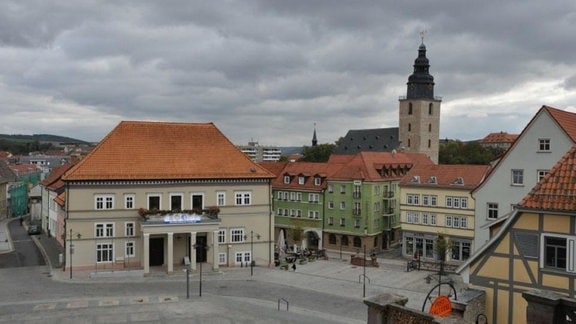 Blick auf das Stadtzentrum von Sondershausen. Am Marktplatz steht das Rathaus, umring von Häuserzeilen. Im Hintergrund steht eine Kirche mit einem hohen Turm.