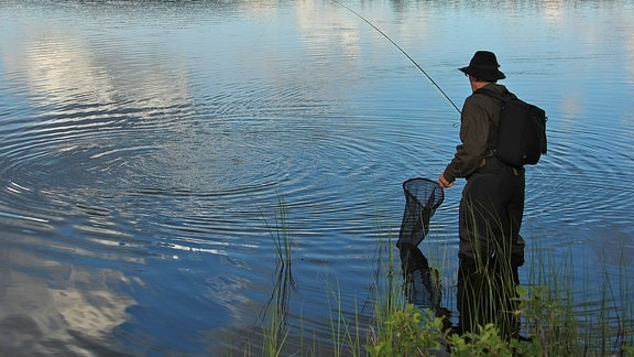 Ein Fliegenfischer steht im Wasser.