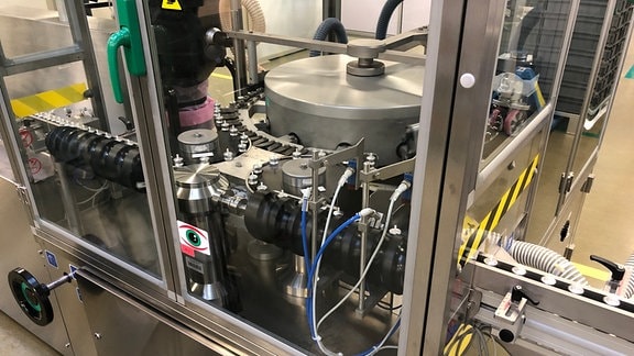 Eine Maschine zur Medikamentenproduktion hat einen silbernen Eisentopf in der Mitte.