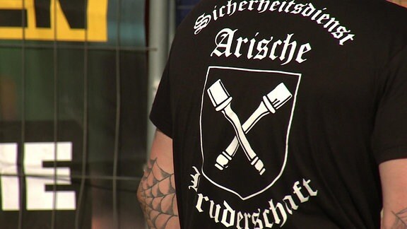 Mann in schwarzem T-Shirt mit der Aufschrift "Sicherheitsdienst Arische Bruderschaft"