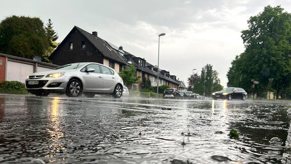 Autos fahren bei einem Gewitter eine teilweise überflutete Straße entlang