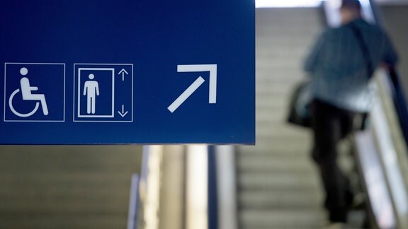 Ein Hinweisschild mit Piktogrammen "Rollstuhlfahrer" und "Fahrstuhl" zeigt 2016 in einem Bahnhof den Weg für Passagiere mit eingeschränkter Mobilität.