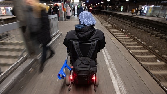 Steffen Gödecke fährt 2019 mit seinem Elektro-Rollstuhl im Bahnhof an einem Gleis.