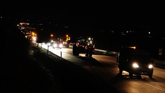 Eine Kolonne aus Traktoren, Transportern und Autos in der Dunkelheit auf der Abfahrt Tiefthal/Kühnhausen B4