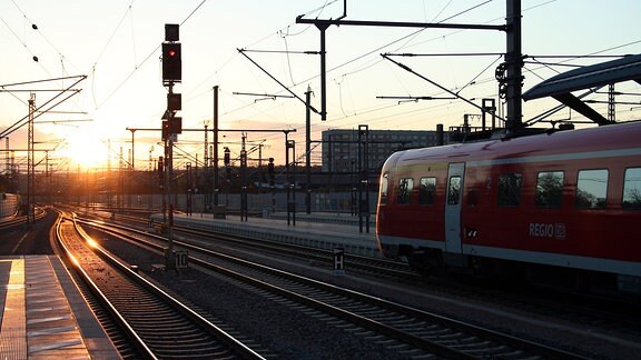 Regionalbahn steht bei Sonnenuntergang am Bahnhof