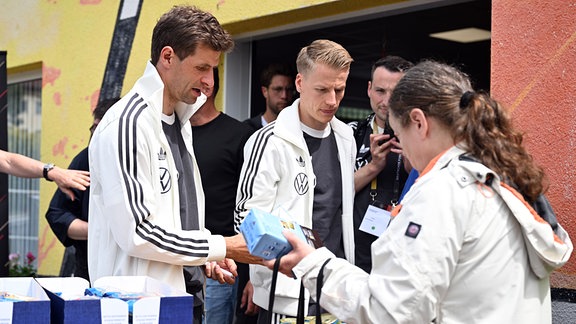 Die Nationalspieler Thomas Müller (l) und Chris Führich geben bei der Blankenhainer Tafel Essen aus.