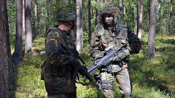 Zwei getarnte Bundeswehr-Soldaten mit dem Sturmgewehr G36 bei einer Übung im Wald..