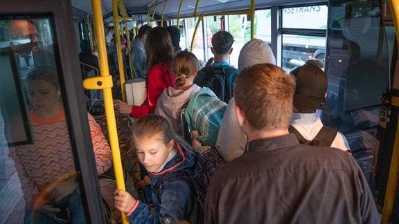 Schülern eng nebeneinander in einem Linienbus