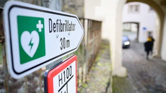Ein Schild zeigt die Richtung an, in der ein Defibrillator hängt.