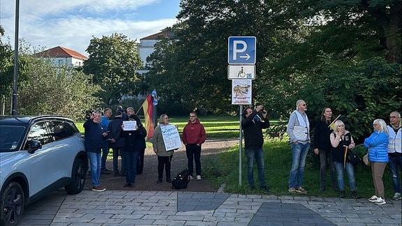 Eine Gruppe Menschen vor dem Thüringer Landtag mit kleinen Deutschland-Flaggen und Plakaten, unter anderem mit der Aufschrift "Der Souverän hat entschieden. Die stärkste Kraft ist nicht die CDU."