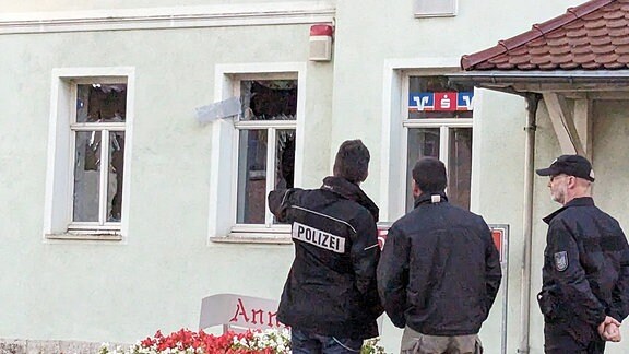 Polizisten stehen vor einem Haus