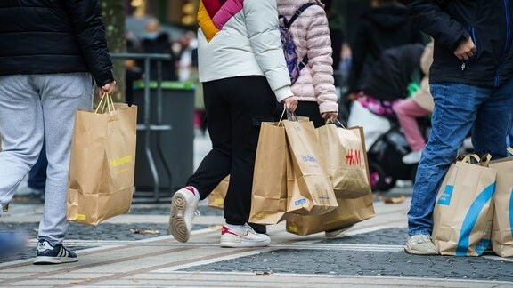Menschen laufen 2021 mit Einkaufstüten durch eine Innenstadt.