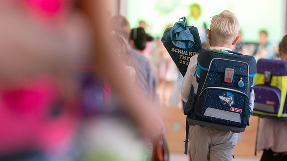 Ein Schüler geht während einer Einschulungsfeier der ersten Klasse an der Wickerbach-Grundschule mit einer Schultüte Richtung Bühne.