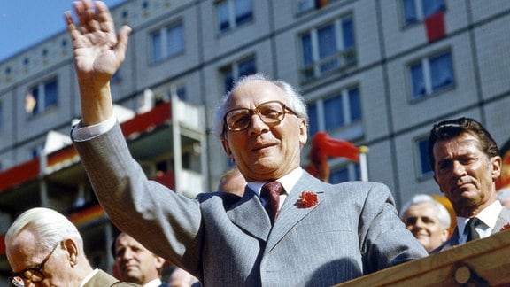 Erich Honecker winkt am 1. Mai 1986 von einer Ehrentribühne in der Berliner Karl-Marx-Allee, links Willi Stoph