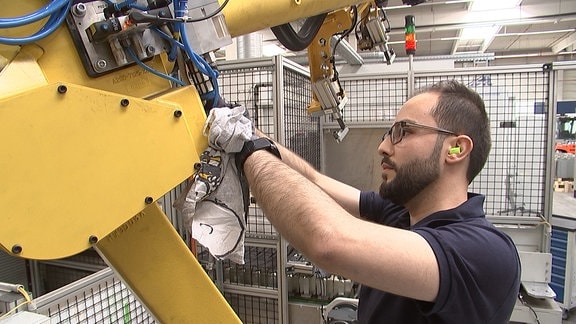 Ein mann arbeitet an einer Maschine ineiner Fabrik.
