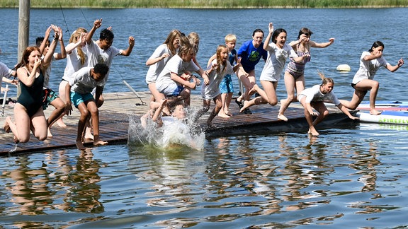 Kinder und Jugendliche springen in der der Ferienanlage in der Perspektivfabrik am Beetzsee in das Wasser.