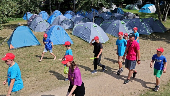 Kinder laufen an Zelten vorbei.