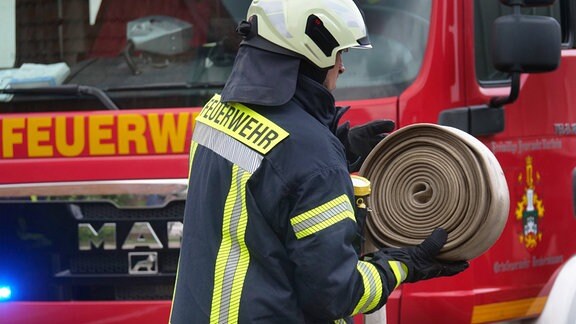 Ein Feuerwehrmann wickelt einen Schlauch auf.