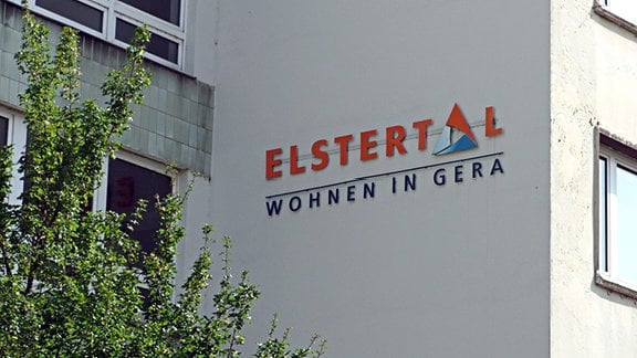 An einer Hauswand ist ein Schriftzug angebracht. Er lautet: GWB Elstertal - Wohnen in Gera. Es handelt sich um das Logo der kommunalen Wohnungsgesellschaft der Stadt Gera.