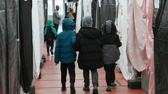 Flüchtlingskinder gehen durch ein Zelt der Flüchtlingsunterkunft.