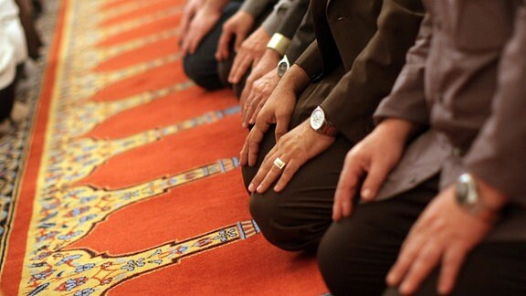 Mehrere Männer knien in einem Gebetsraum nebeneinander.