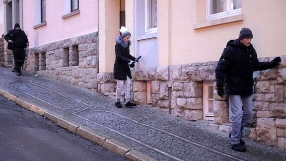In Eisenach tasten sich Fußgänger vorsichtig an Hauswänden einen abschüssigen Gehweg hinab.