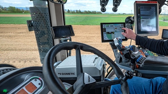 Ein Landwirt fährt in einem Traktor mit GPS-Lenksystem auf einem Acker
