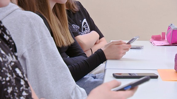 Schüler schauen im Unterricht auf ein Handy. 