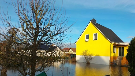 Ein von Wasser überflutetes Grundstück, im Hintergrund ein Haus
