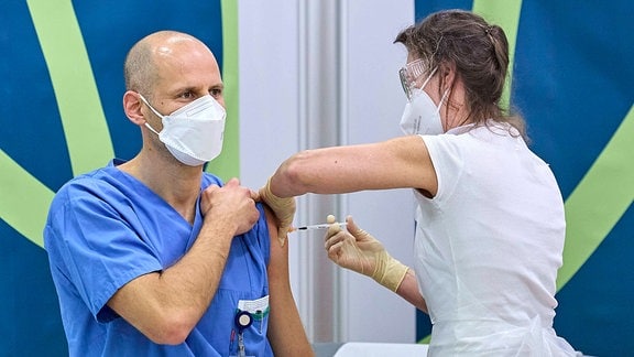Der Mitarbeiter eines Krankenhauses erhält seine erste Impfdosis.