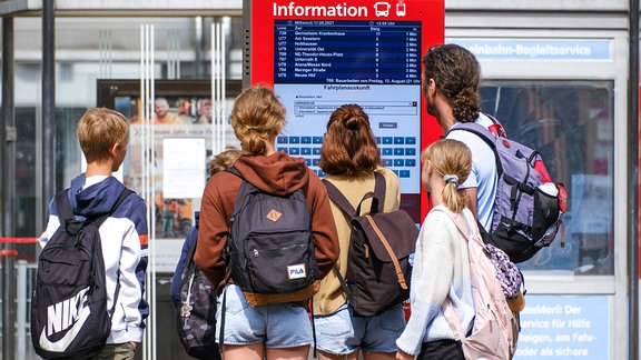 Jugendliche stehen vor einem Info-Terminal der Deutschen Bahn