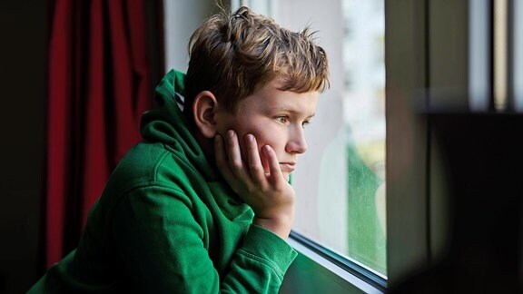Ein Junge schaut aus einem Fenster