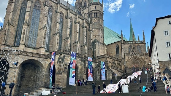 Blick auf den Erfurter Dom und die Domstufen. Hier rollen Mitarbeiter gerade ein großes Banner auf den Stufen aus.