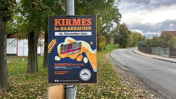 Ein Plakat für die Kirmes in Haarhausen hängt an einem Laternenpfahl.