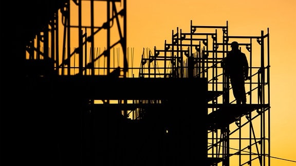 Bauarbeiter errichten bei Sonnenaufgang ein Gebäude am Kronberg