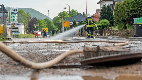 Feuerwehrmann säubert die Straße mit Wasser aus einem Schlauch.