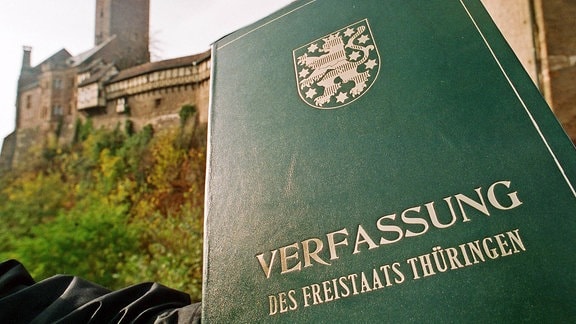 Ein Mann hält 1993 vor der Wartburg in Eisenach die Thüringer Verfassung in den Händen