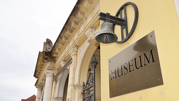 Das Glockenmuseum in Apolad: An der Fassade hängt ein Schild mit der Aufschrift "Museum". Über dem Schild hängt eine Glocke. 