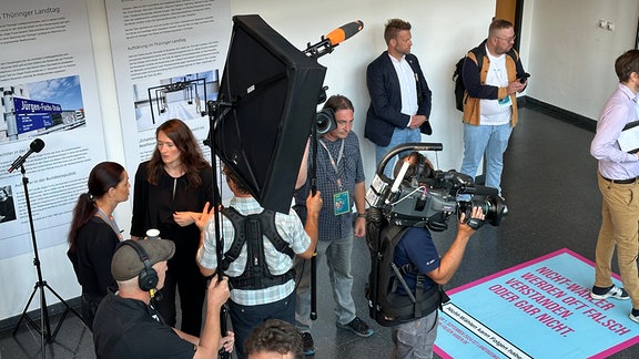 Mehrere Menschen stehen mit Kameratechnik in einem weitläufigen Foyer.