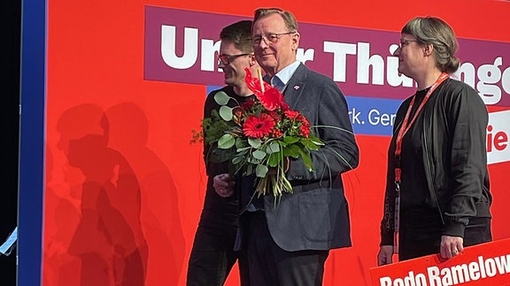 Thüringens Ministerpräsident Bodo Ramelow betritt Bühne mit Blumenstrauß