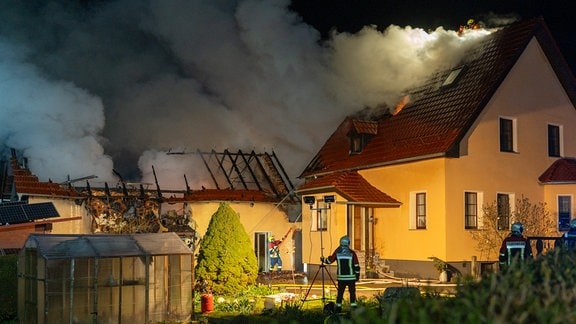 Feuerwehrleute an einem brennenden Haus.