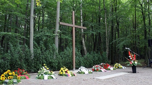 Niedergelegte Kränze vor Kreuz auf dem Trauerplatz