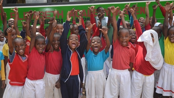 Schulkinder in Kenia freuen sich und reißen die Hände hoch